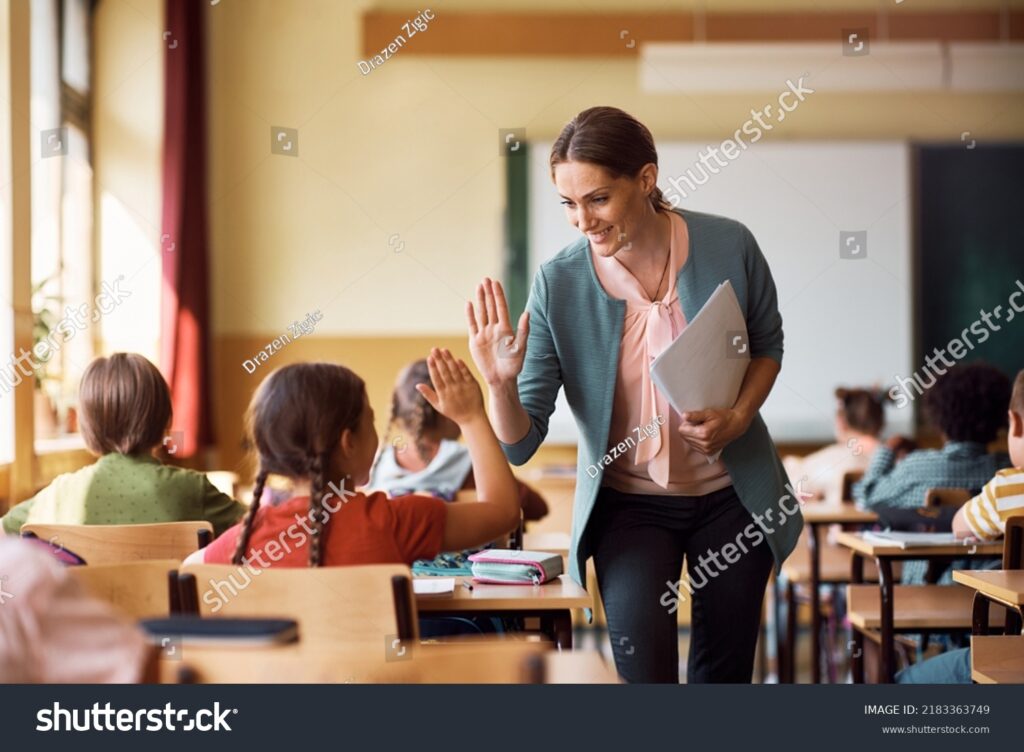 stock-photo-happy-elementary-school-teacher-giving-high-five-to-her-student-during-class-in-the-classroom-2183363749 - Restore American Schools